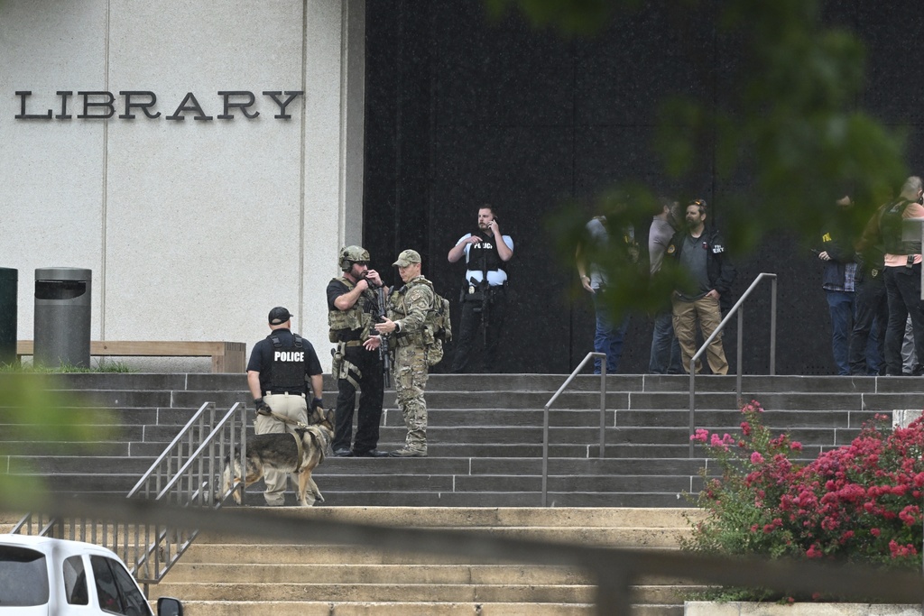 Law enforcement officers gather in front of the library on the University of Arkansas campus while responding to reports of a shooting Monday, Aug. 25, 2025, in Fayetteville, Ark. (AP Photo/Michael Woods)