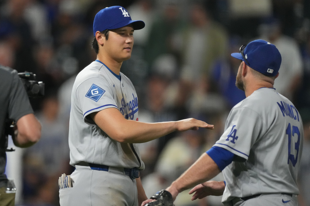 Los Angeles Dodgers' Shohei Ohtani, left, congratulates third baseman Max Muncy, right, after defeating the Colorado Rockies in a baseball game Monday, April 20, 2026, in Denver. (AP Photo/David Zalubowski)
