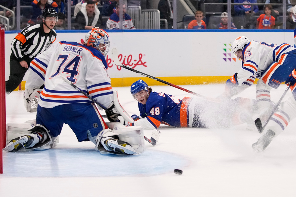 Edmonton Oilers goaltender Stuart Skinner (74) and Isaac Howard (53) protect the net from New York Islanders' Matthew Schaefer (48) during the second period of an NHL hockey game Thursday, Oct. 16, 2025, in Elmont, N.Y. (AP Photo/Frank Franklin II)