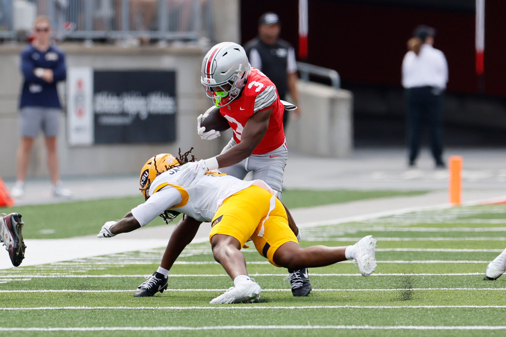 Ohio State wide receiver Devin McCuin, top, is tackled by Kent State defensive back Derrick Jackson during the first half of an NCAA college football game, Saturday, Sept. 19, 2026, in Columbus, Ohio. (AP Photo/Jay LaPrete)