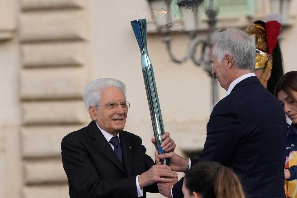 Organizing Committee President Giovanni Malagò passes the torch to the Italian President Sergio Mattarella during the Milan Cortina 2026 Winter Olympics cauldron lighting in front of the Quirinale Presidential Palace, in Rome, Friday Dec. 5, 2025. (AP Photo/Gregorio Borgia)