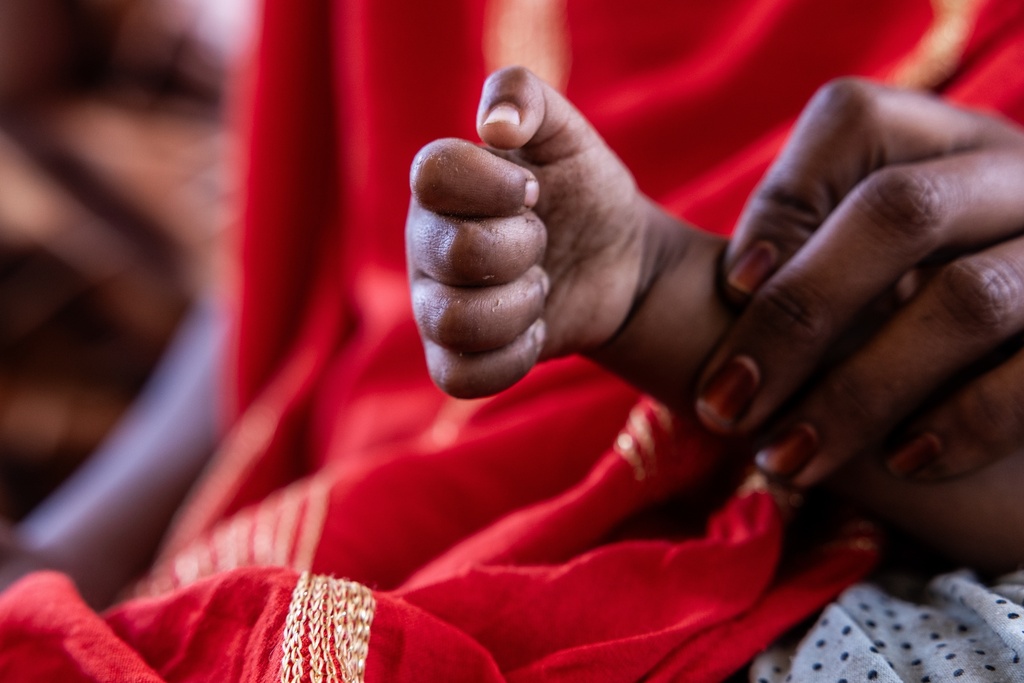 A mother holds the clenched hand of her daughter, who has not unclenched it in the eight months since fleeing mercenaries in Mali and finding refuge in Douankara, Mauritania, Saturday, Nov. 8, 2025. (AP Photo/Caitlin Kelly)