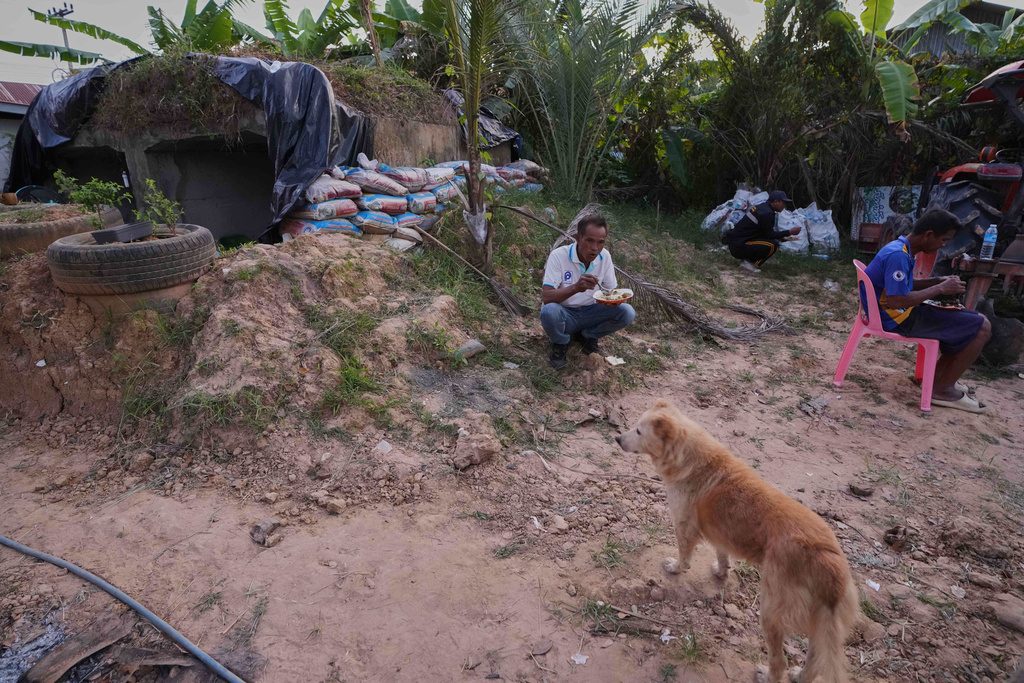 Village security volunteers eat dinner outside a shelter during Thai and Cambodian soldiers clashes in Surin province, Thailand, Tuesday, Dec. 9, 2025. (AP Photo/Sakchai Lalit)