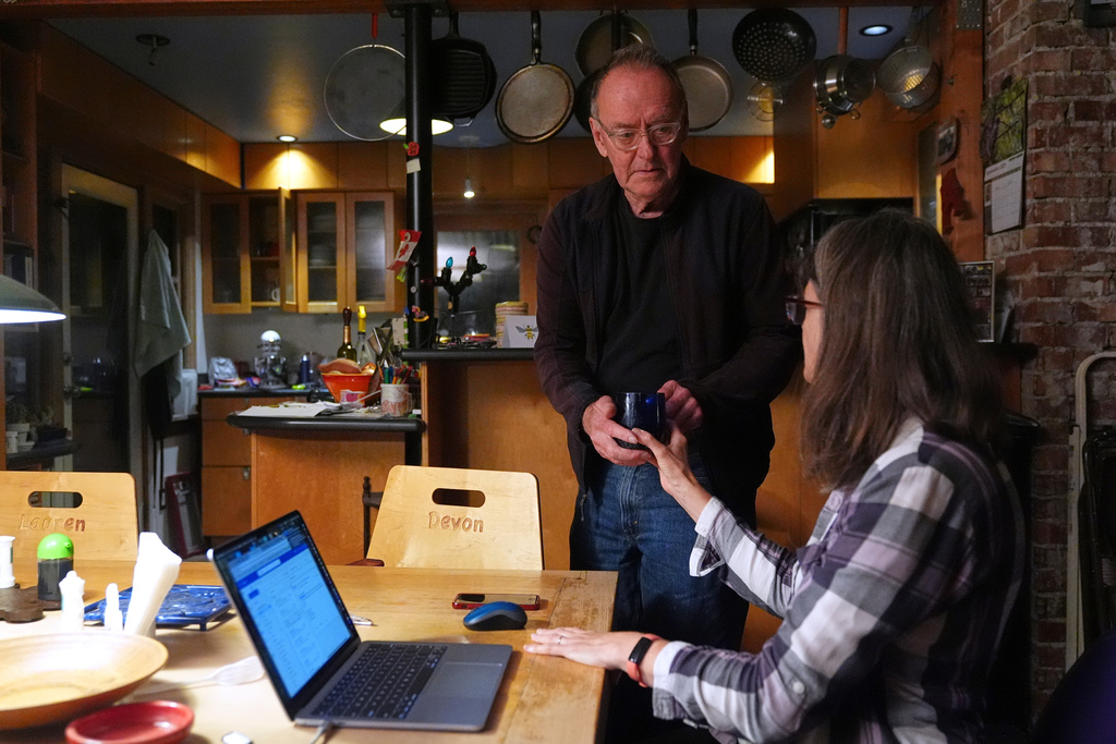 Ross Colquhoun hands his wife Mary E. Brunkow a cup of coffee after hearing about her winning a Nobel Prize in medicine for part of her work on peripheral immune tolerance, in Seattle, Monday, Oct. 6, 2025. (AP Photo/Lindsey Wasson)