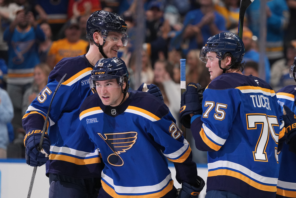 St. Louis Blues' Jimmy Snuggerud (21) is congratulated by Colton Parayko, left, and Tyler Tucker (75) after scoring during the second period of an NHL hockey game against the Dallas Stars Saturday, Oct. 18, 2025, in St. Louis. (AP Photo/Jeff Roberson)