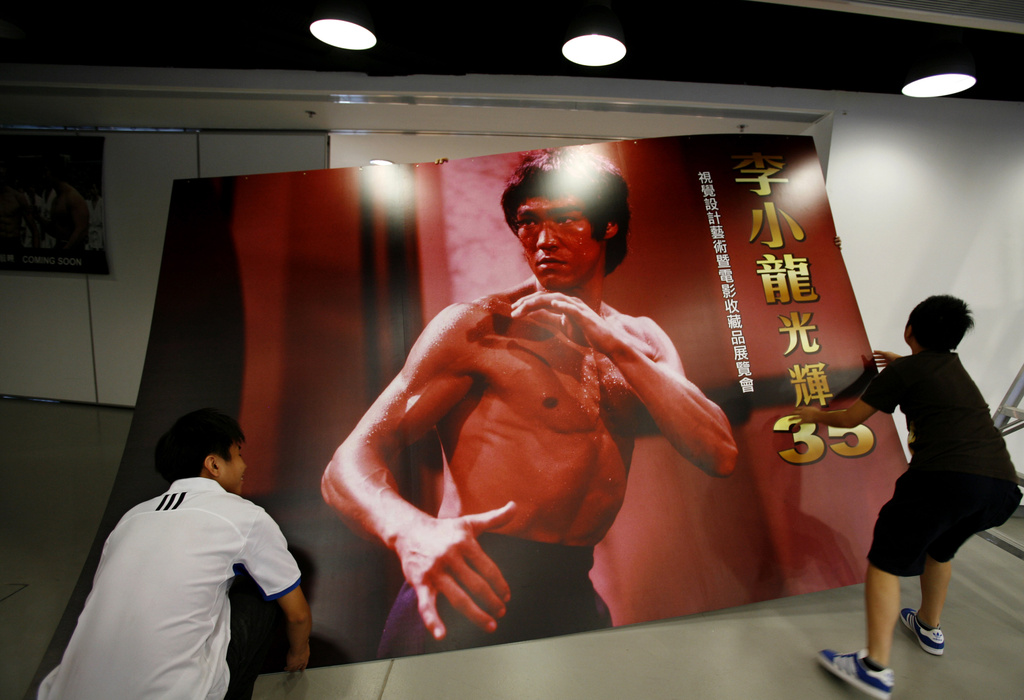FILE - Workers carry a poster of Bruce Lee as part of an exhibition marking the 35th anniversary of his death, on July 18, 2008, in Hong Kong. (AP Photo/Vincent Yu, File)