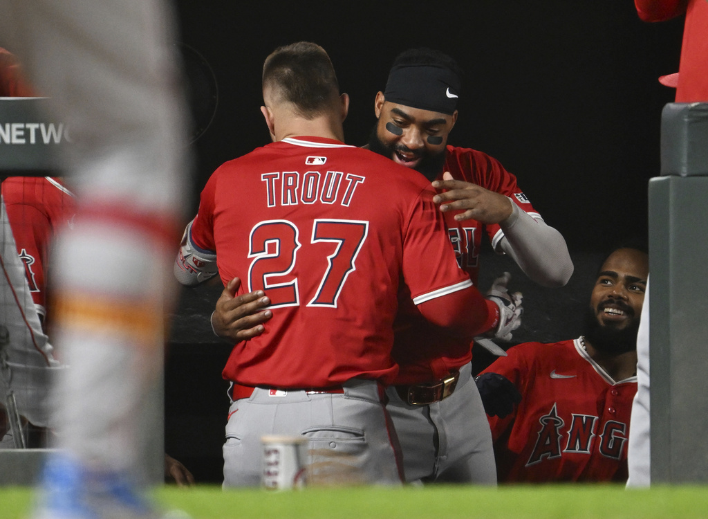 Los Angeles Angels designated hitter Mike Trout, left, is hugged by teammate Jo Adell after returning to the dugout following his home run in the eighth inning against the Colorado Rockies on Saturday, Sept. 20, 2025, in Denver. (AP Photo/RJ Sangosti)