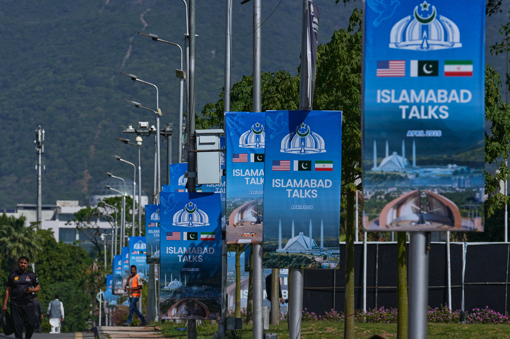Workers walk past billboards near the Serena Hotel ahead of the second round of negotiations between the U.S. and Iran, in Islamabad, Pakistan, Monday, April 20, 2026. (AP Photo/Anjum Naveed)