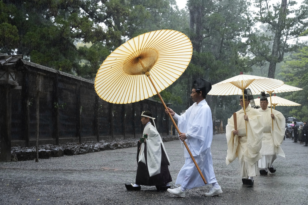 Shinto priests and a girl called "monoimi" march into the main palace of Toyoukedaijingu, also known as Geku, or the outer sanctuary, of the Ise Jingu shrine complex as they begin Yamaguchisai, a kickoff ceremony of Shikinen Sengu, which concludes in 2033, in Ise, central Japan, Friday, May 2, 2025. (AP Photo/Hiro Komae)