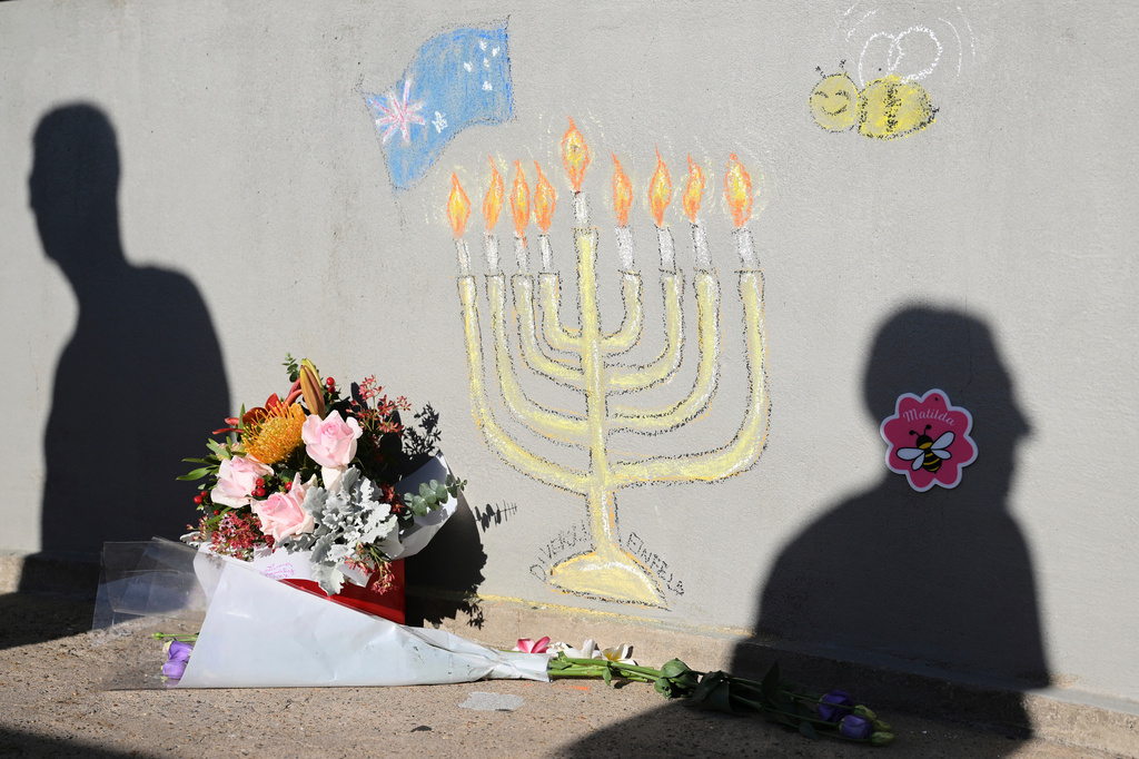 FILE - People walk past a memorial drawn on the wall of a walk bridge as a tribute following Sunday's shooting at Bondi Beach, in Sydney, Friday, Dec. 19, 2025. (AP Photo/Steve Markham, file)