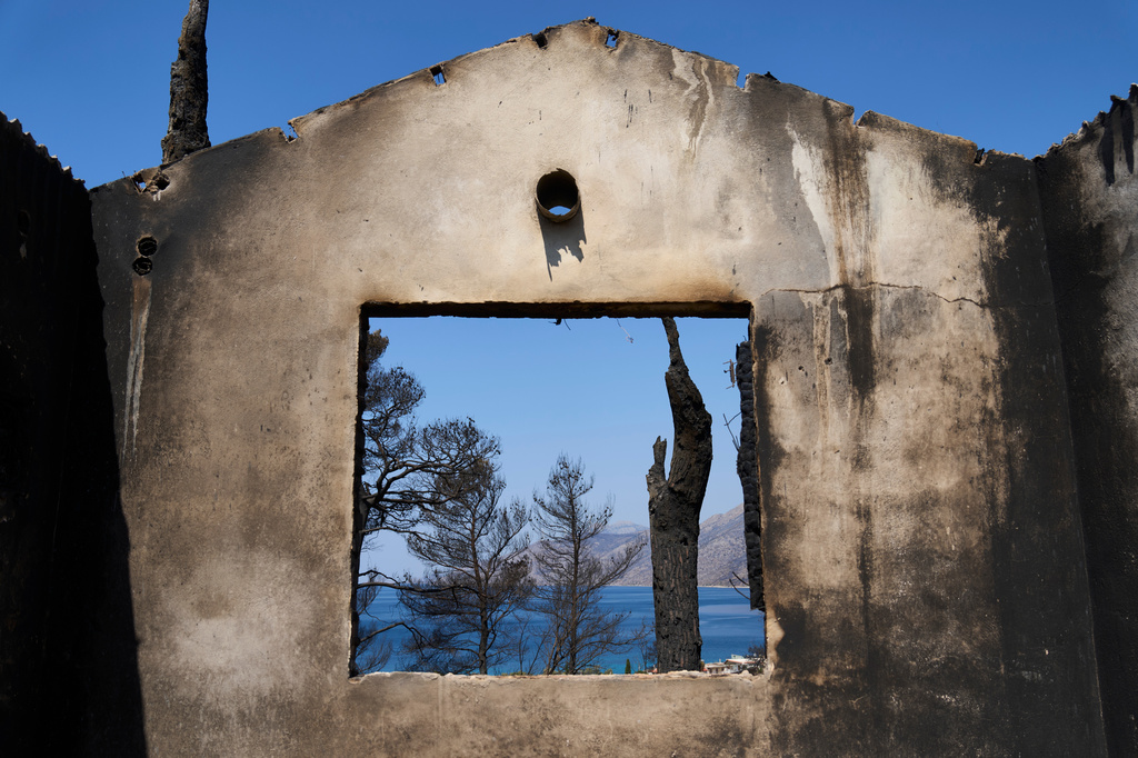 The sea is visible through the remains of a house destroyed by a wildfire in Porto Germeno, northwest of Athens, Greece, Tuesday, Aug. 4, 2026. (AP Photo/Petros Giannakouris)