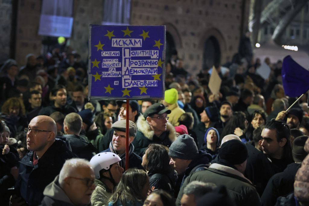 A protester holds a banner as as a swelling crowd of tens of thousands of Bulgarians filled Sofia's central square, demanding the government's resignation amid rising anger over corruption and contested economic policies, Sofia, Bulgaria, Wednesday, Dec. 10, 2025. (AP Photo/Valentina Petrova)