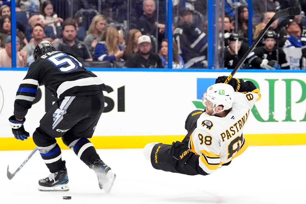 Tampa Bay Lightning defenseman Charle-Edouard D'Astous (51) knocks down Boston Bruins right wing David Pastrnak (88) during the third period of an NHL hockey game Saturday, April 4, 2026, in Tampa, Fla. (AP Photo/Chris O'Meara)