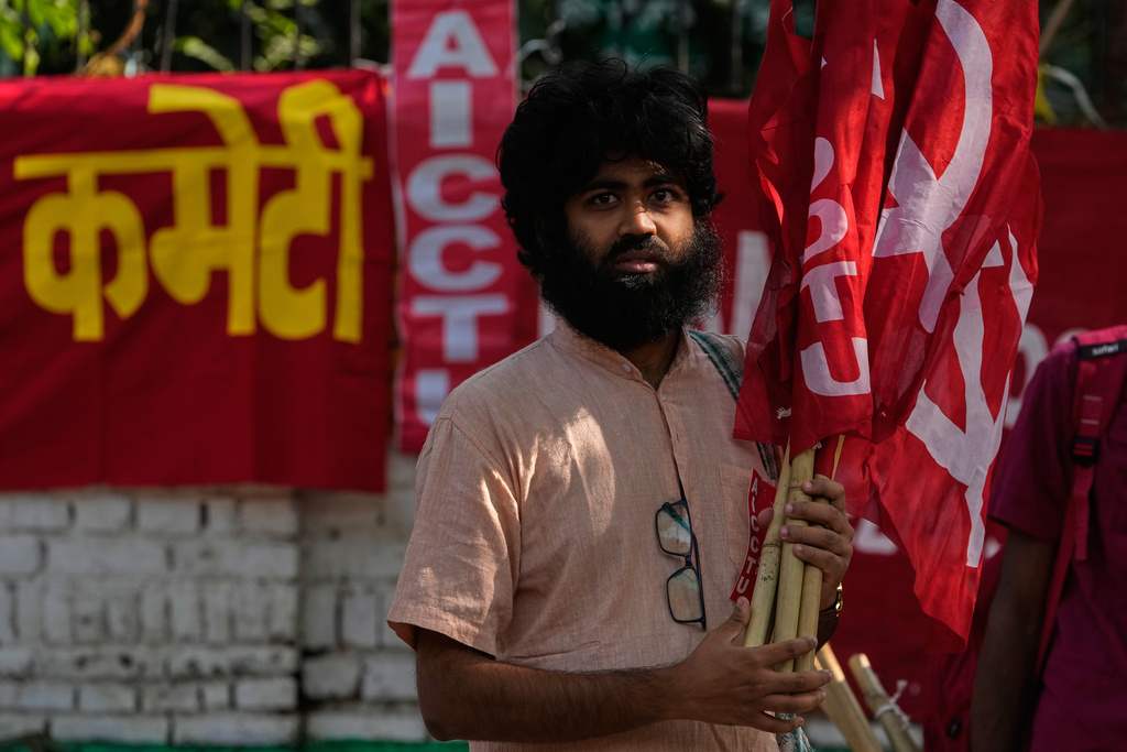 An activist of a trade union carries flags for distribution to fellow activist during a protest against the government's rollout of new labor codes in New Delhi, India, Wednesday, Nov. 26, 2025. (AP Photo/Manish Swarup)