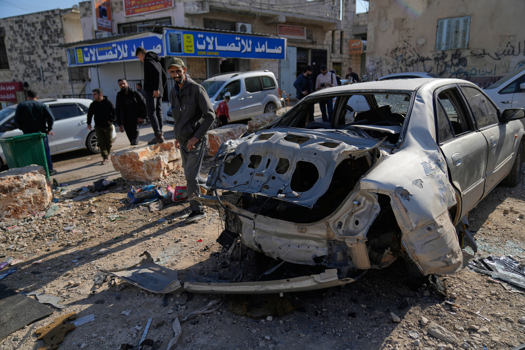 Residents inspect a destroyed vehicle after an Israeli army raid that left one Palestinian killed, in the West Bank town of Qabatiya Thursday, Nov. 27, 2025. (AP Photo/Nasser Nasser)