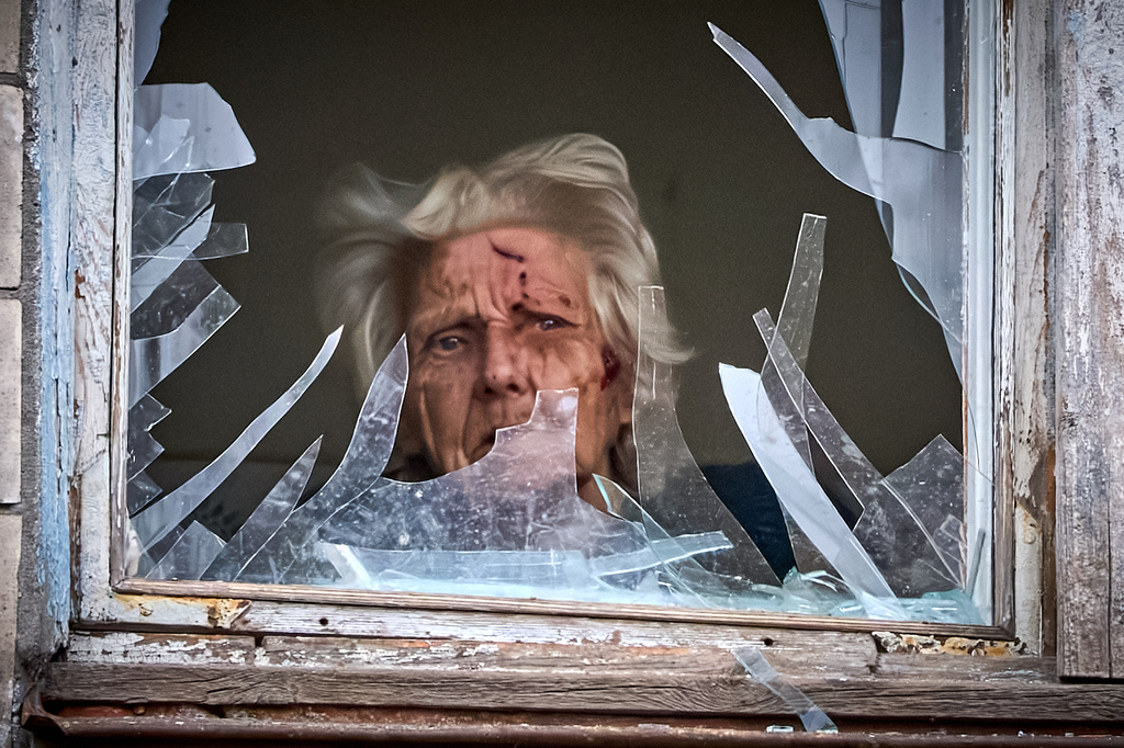 FILE - An injured elderly woman looks out of her broken window as an apartment building was hit by a Russian drone during an aerial attack in Kyiv, Ukraine, Dec. 23, 2025. (AP Photo/Efrem Lukatsky, File)