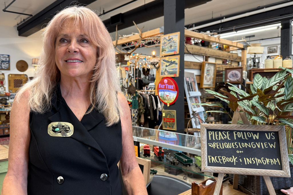 Cindy Stiebritz poses for a photo in the antiques shop where she volunteers in Longview, Wash. on May 27, 2026. (AP Photo/Claire Rush)