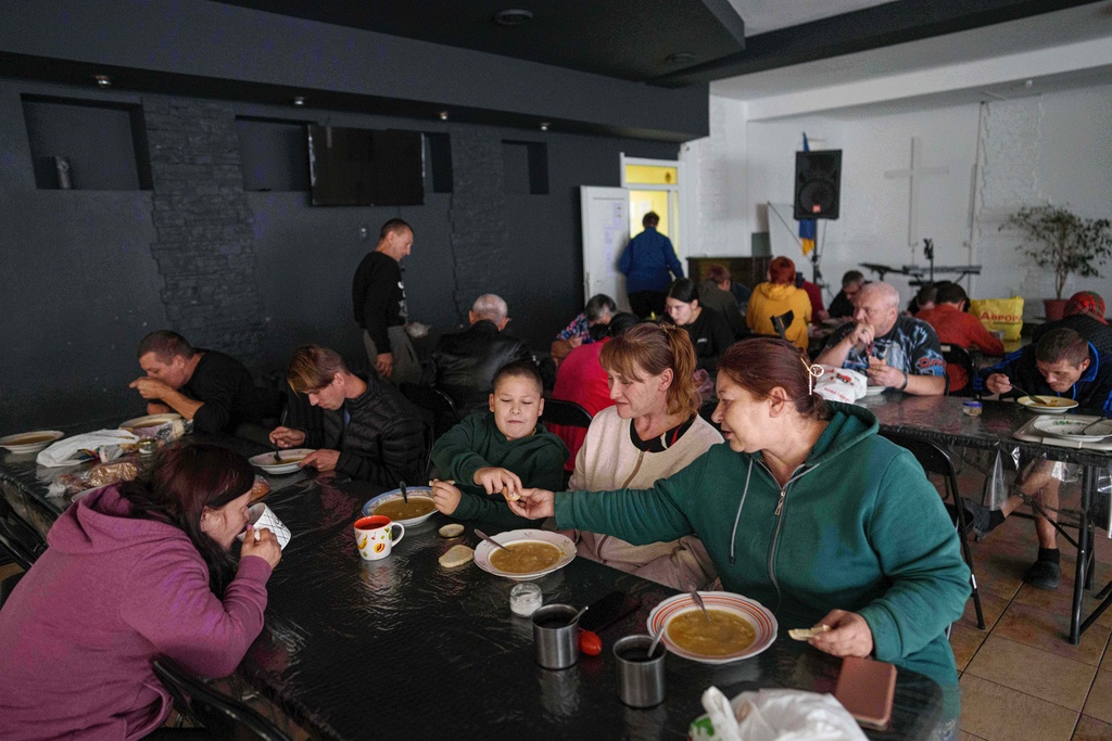 People eat at a hostel for the displaced in Dnipro, Ukraine, Wednesday, Oct. 8, 2025. (AP Photo/Evgeniy Maloletka)
