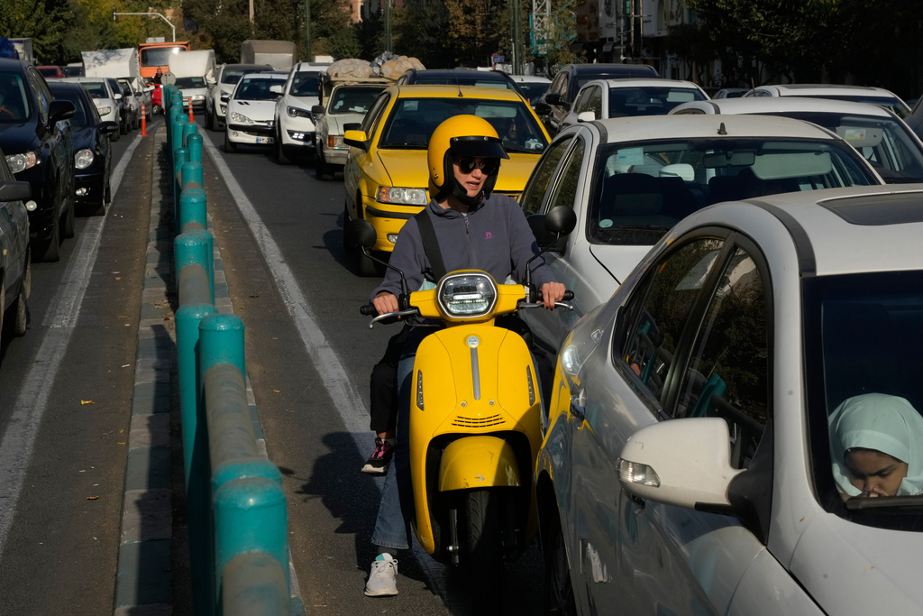 A woman drives her motorbike in northern Tehran, Iran, Saturday, Nov. 1, 2025. (AP Photo/Vahid Salemi)