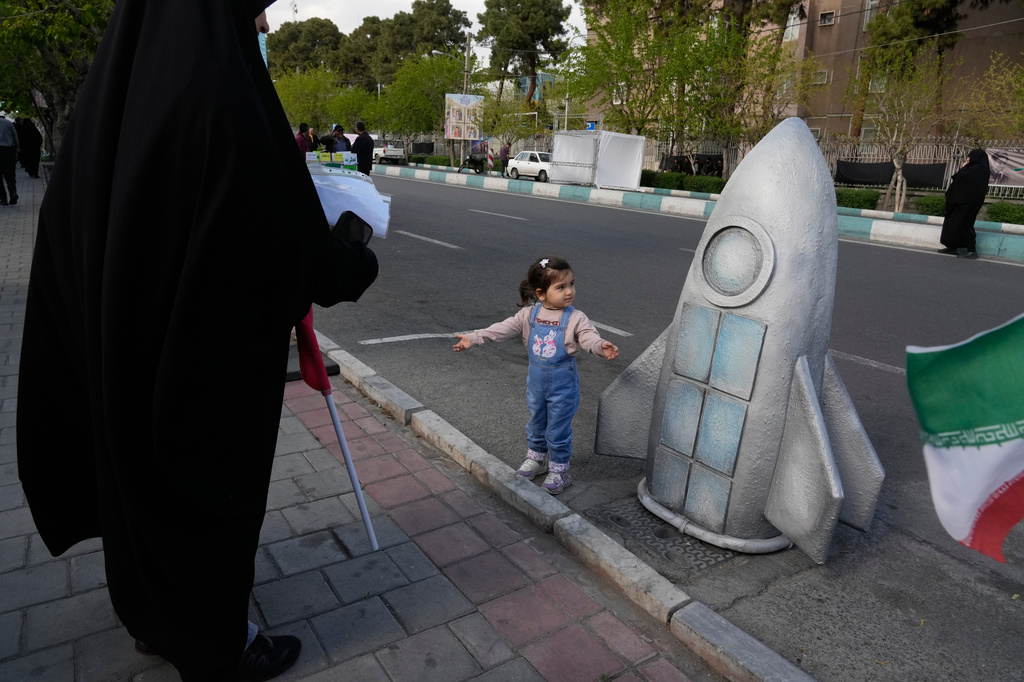A girl stands next to replica of a space craft in a memorial for school children who were killed during a strike on a school in southern town of Minab on Feb. 28, in downtown Tehran, Iran, Tuesday, April 7, 2026. (AP Photo/Vahid Salemi)