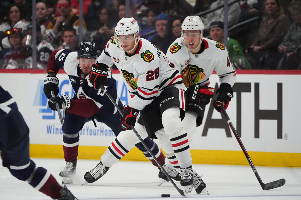 Chicago Blackhawks left wing Andre Burakovsky, front, collects the puck as defenseman Louis Crevier, back right, and Colorado Avalanche right wing Valeri Nichushkin pursue in the second period of an NHL hockey game Saturday, Feb. 28, 2026, in Denver. (AP Photo/David Zalubowski)