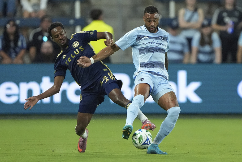 Vancouver Whitecaps midfielder Ali Ahmed, left, tries to steal the ball from Sporting Kansas City defender Khiry Shelton, right, during the first half of an MLS soccer match Saturday, Sept. 20, 2025, in Kansas City, Kan. (AP Photo/Charlie Riedel)