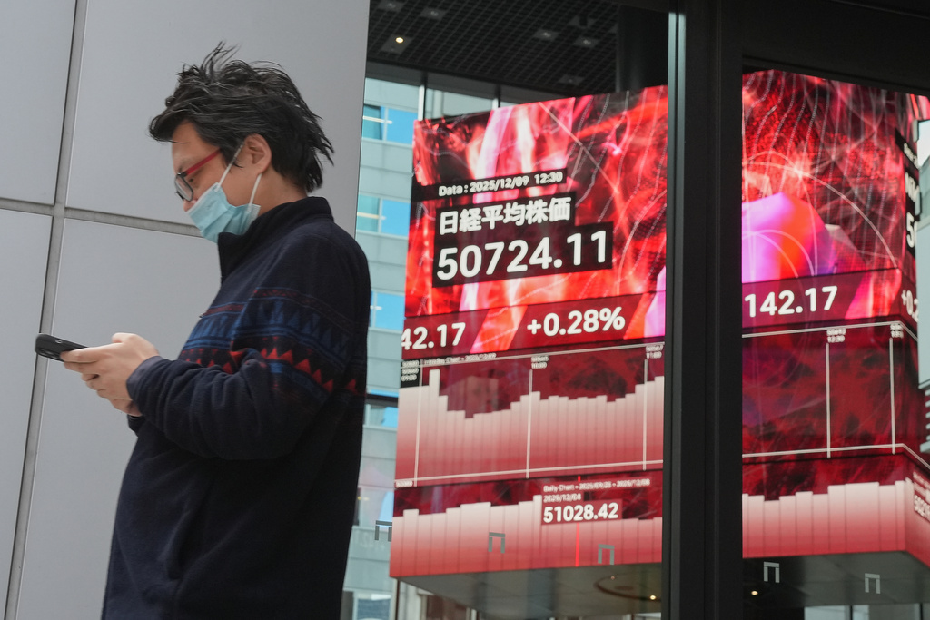 A person walks in front of an electronic stock board showing Japan's Nikkei index at a securities firm Tuesday, Dec. 9, 2025, in Tokyo. (AP Photo/Eugene Hoshiko)