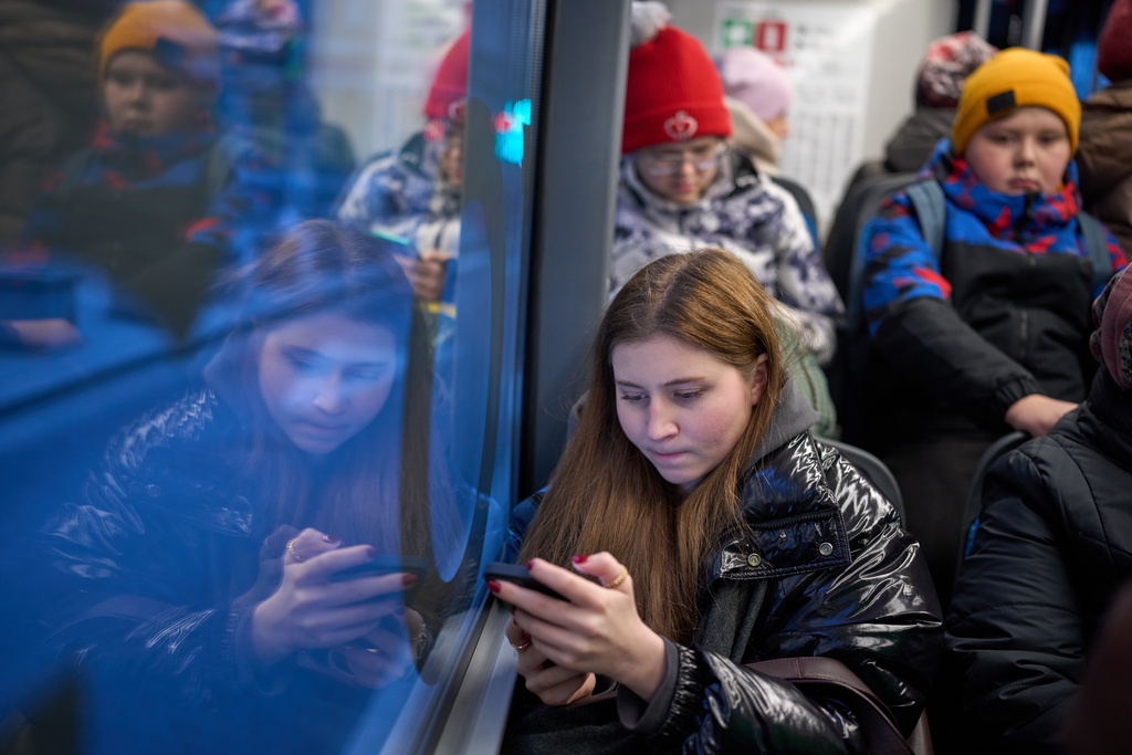 FILE - A woman looks at her smartphone on a bus in Moscow, Russia, Wednesday, Dec. 3, 2025. (AP Photo/Alexander Zemlianichenko, File)