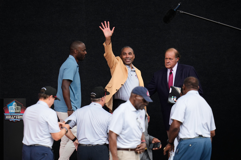 Former NFL player Roger Craig, center, waves after unveiling his bust during the Pro Football Hall of Fame induction ceremony at the Pro Football Hall of Fame, in Canton, Ohio, Saturday, Aug. 8, 2026. (AP Photo/Sue Ogrocki)