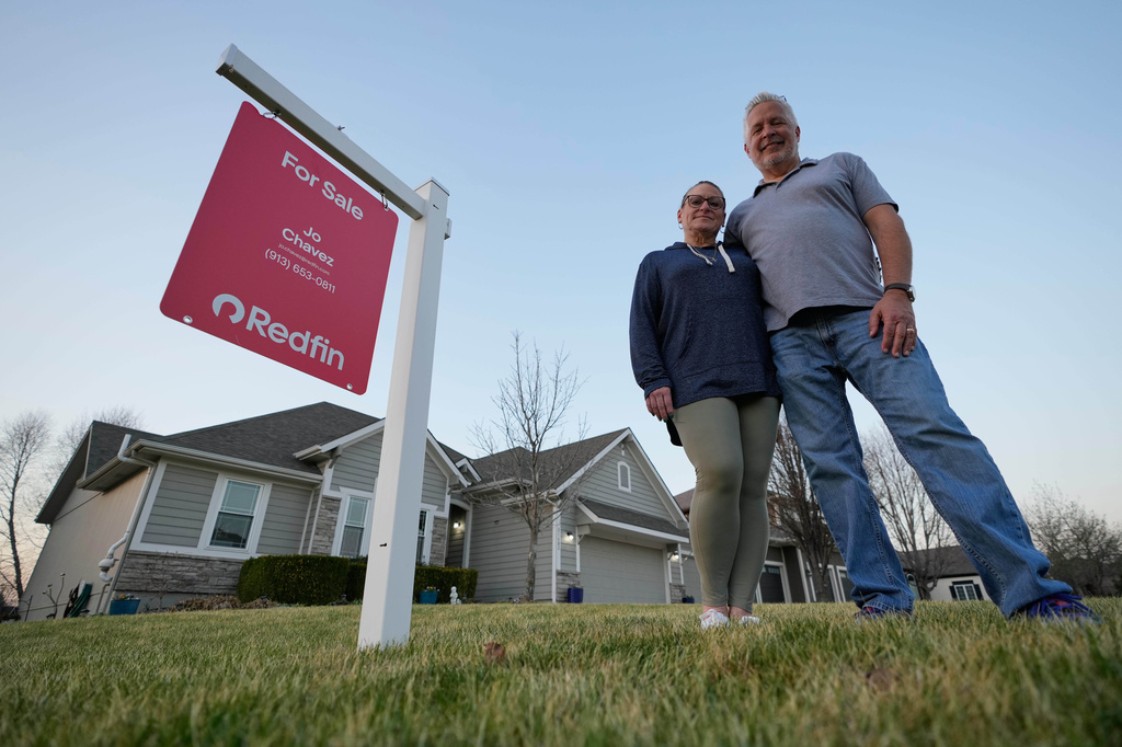 Gail and David Sanders stand in front of their home which they have been trying to sell Wednesday, March 25, 2026, in Olathe, Kan. (AP Photo/Charlie Riedel)