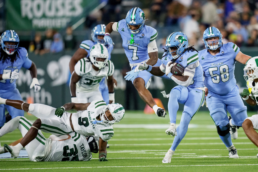 Tulane running back Jamauri McClure (25) runs away from Charlotte defensive back Cary Grant (9) and linebacker Shay Taylor (35) during the first half of an NCAA college football game in New Orleans, Saturday, Nov. 29, 2025. (AP Photo/Matthew Hinton)