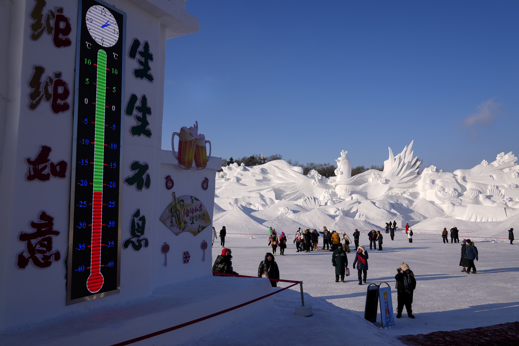 Visitors tour near a giant snow sculpture near a thermometer on display at the Sun Island Park during the Harbin Ice and Snow World in Harbin, China's Heilongjiang province on Wednesday, Jan. 8, 2025. (AP Photo/Andy Wong)