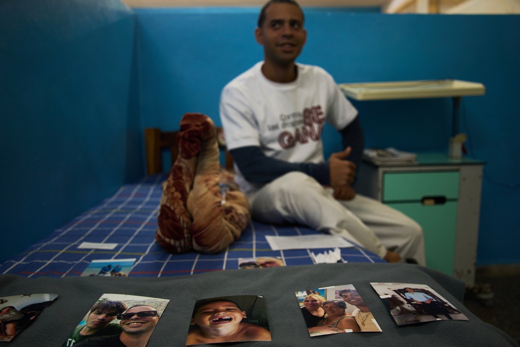 A youth in rehabilitation sits on his bed next to photos of his family that he uses as support for his recovery at a psychiatric hospital in Havana, Cuba, Wednesday, Feb. 25, 2026. (AP Photo/Ramon Espinosa)