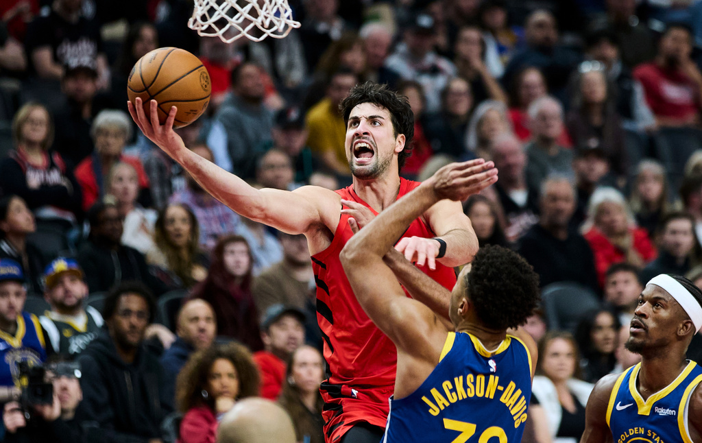 Portland Trail Blazers forward Deni Avdija, top, shoots over Golden State Warriors forward Trayce Jackson-Davis, bottom and forward Jimmy Butler III, right, during the first half of an NBA basketball game in Portland, Ore., Sunday, Dec. 14, 2025. (AP Photo/Craig Mitchelldyer)