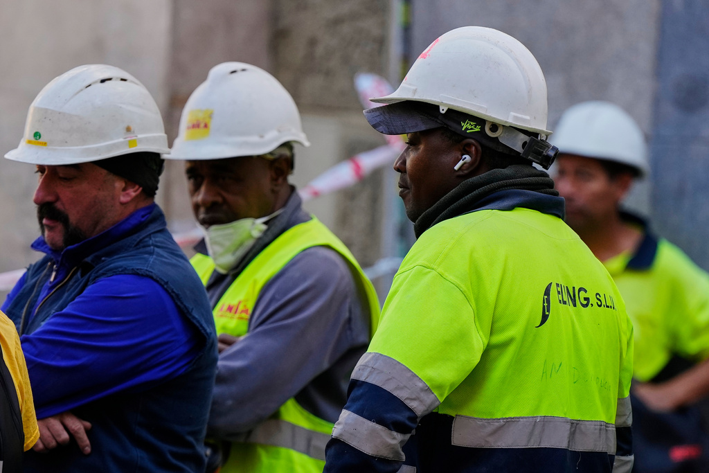 Workers wait near the site of a building collapse in Madrid, Spain, Tuesday, Oct. 7, 2025. (AP Photo/Manu Fernandez)