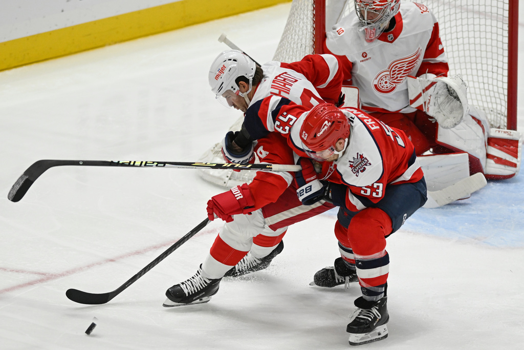 Detroit Red Wings defenseman Ben Chiarot, left, battles for the puck against Washington Capitals center Ethen Frank in front of Red Wings goaltender John Gibson during the third period of an NHL hockey game, Saturday, Dec. 20, 2025, in Washington. (AP Photo/John McDonnell)