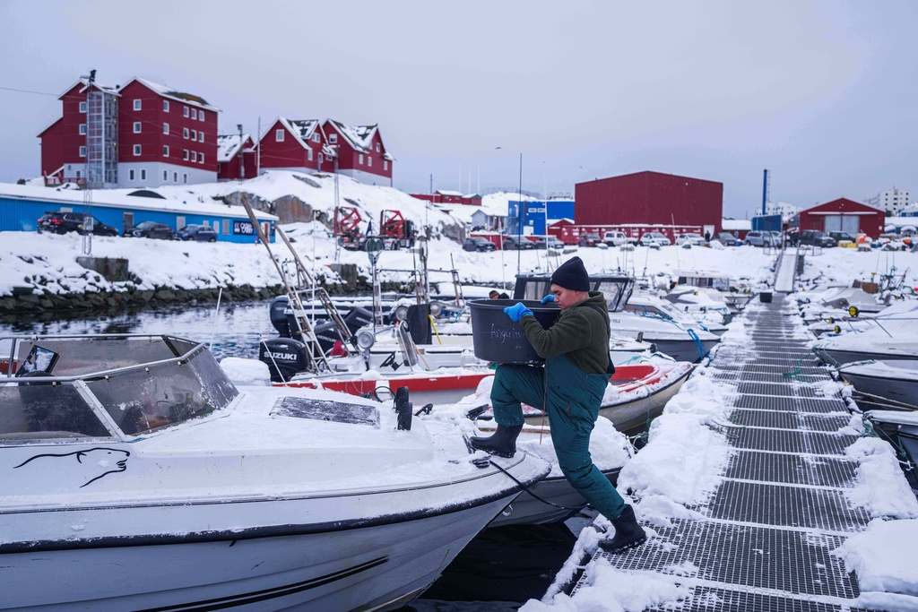 A fisherman carries a bucket onto his boat in the harbor of Nuuk, Greenland, on Tuesday, Jan. 13, 2026. (AP Photo/Evgeniy Maloletka)