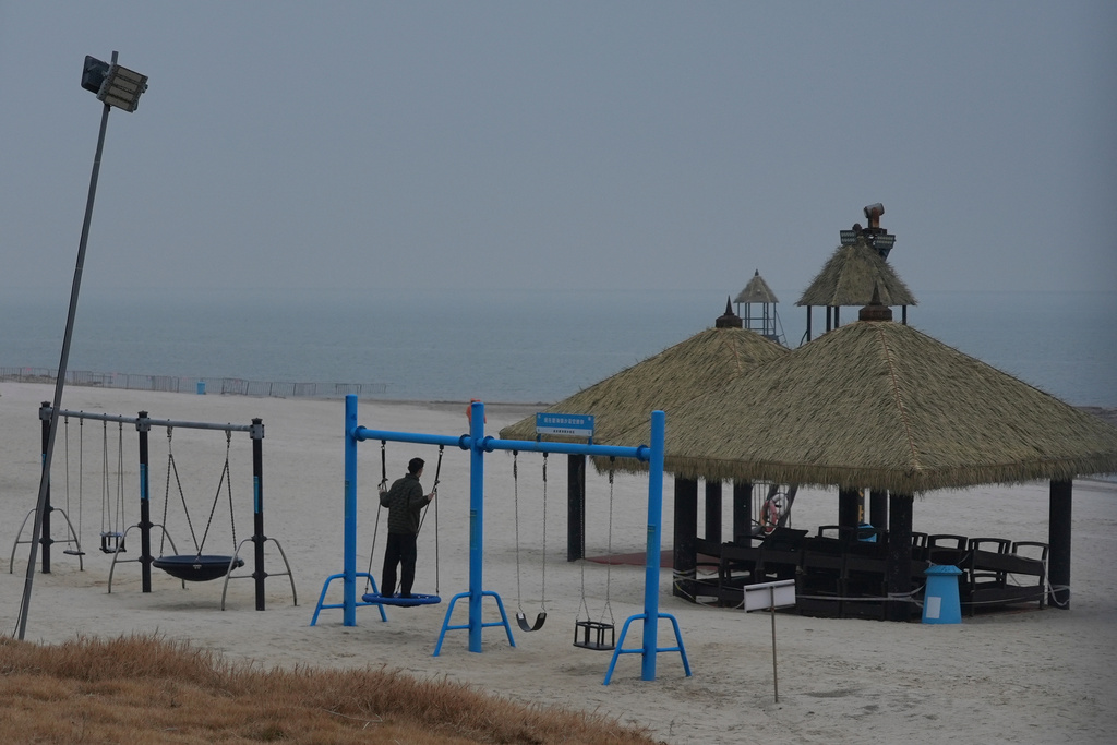 A man swings on an empty beach at the semi-abandoned "Life in Venice" housing complex in Qidong, on China's east coast, Feb. 5, 2026. (AP Photo/Dake Kang)