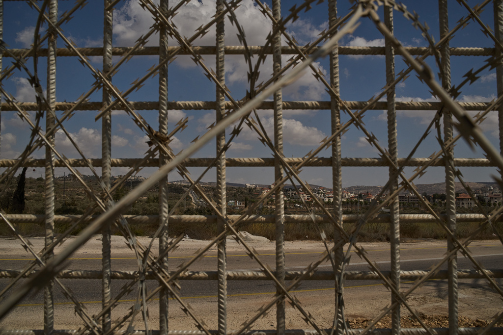 The town of Turmus Ayya is seen through a fence built by Israeli authorities that surrounds the West Bank village of Sinjil, Tuesday, Sept. 30, 2025. (AP Photo/Leo Correa)