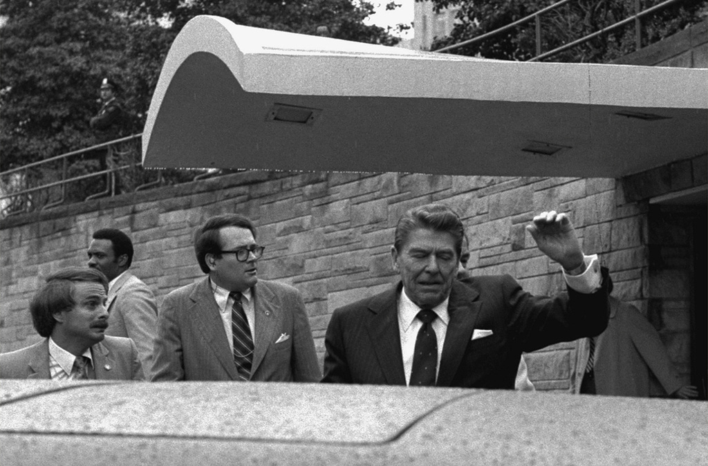 FILE - President Ronald Reagan winces and raises his left arm as he was shot by an assailant as he left a Washington hotel, Monday, March 30, 1981. (AP Photo/Ron Edmonds, File)