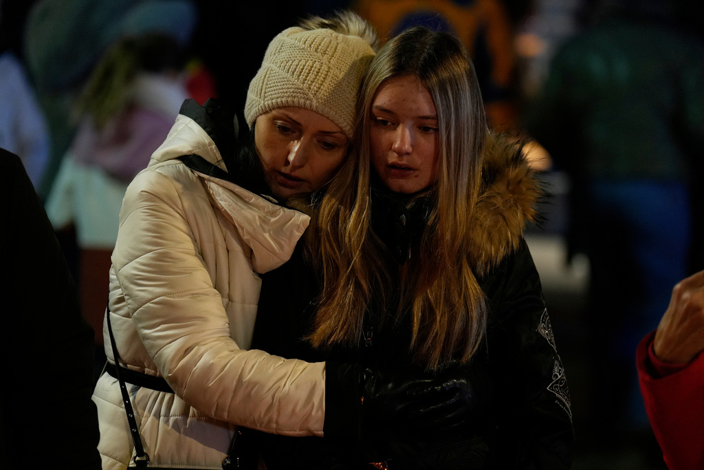 People mourn near the sealed off Le Constellation bar in Crans-Montana, Swiss Alps, Switzerland, Friday, Jan. 2, 2026, where a devastating fire left dead and injured during the New Year's celebrations. (AP Photo/Baz Ratner)
