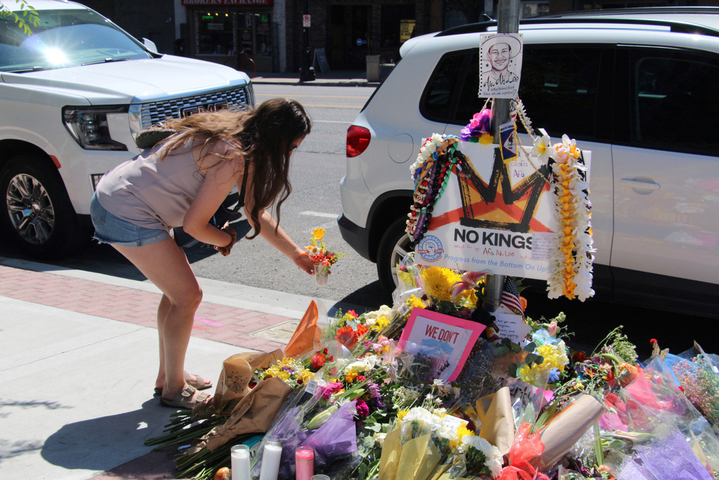 FILE - A woman lays flowers, June 17, 2025, at a makeshift memorial for Arthur Folasa Ah Loo, known to friends and family as Afa, on the city block in Salt Lake City, where Ah Loo was fatally shot during a "No Kings" protest on June 14. (AP Photo/Hannah Schoenbaum, file)