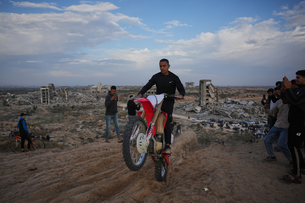 A Palestinian man rides his motorcycle on a sand dune in the Al-Zahra area, in the central Gaza Strip, Friday, Dec. 5, 2025. (AP Photo/Abdel Kareem Hana)
