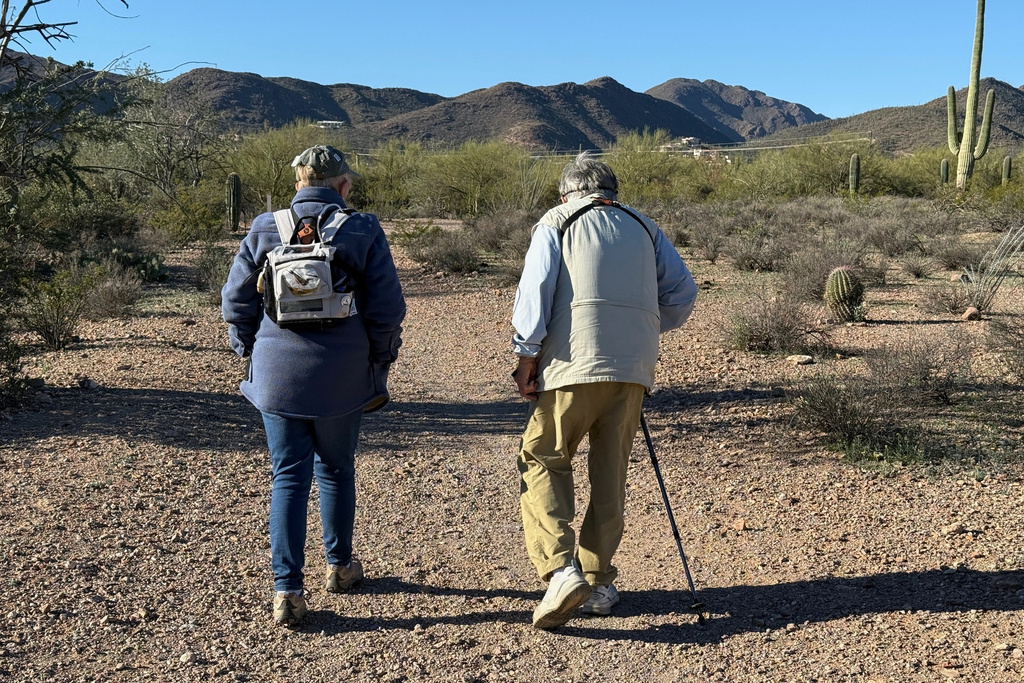 Group leader Marcia OBara, left, wearing an oxygen pack for her COPD, and birding enthusiast Rhea Guertin walk down a smooth dirt path during an accessible outing at Feliz Paseos Park in Tucson, Ariz., on Feb. 4, 2026. (Anita Snow via AP)