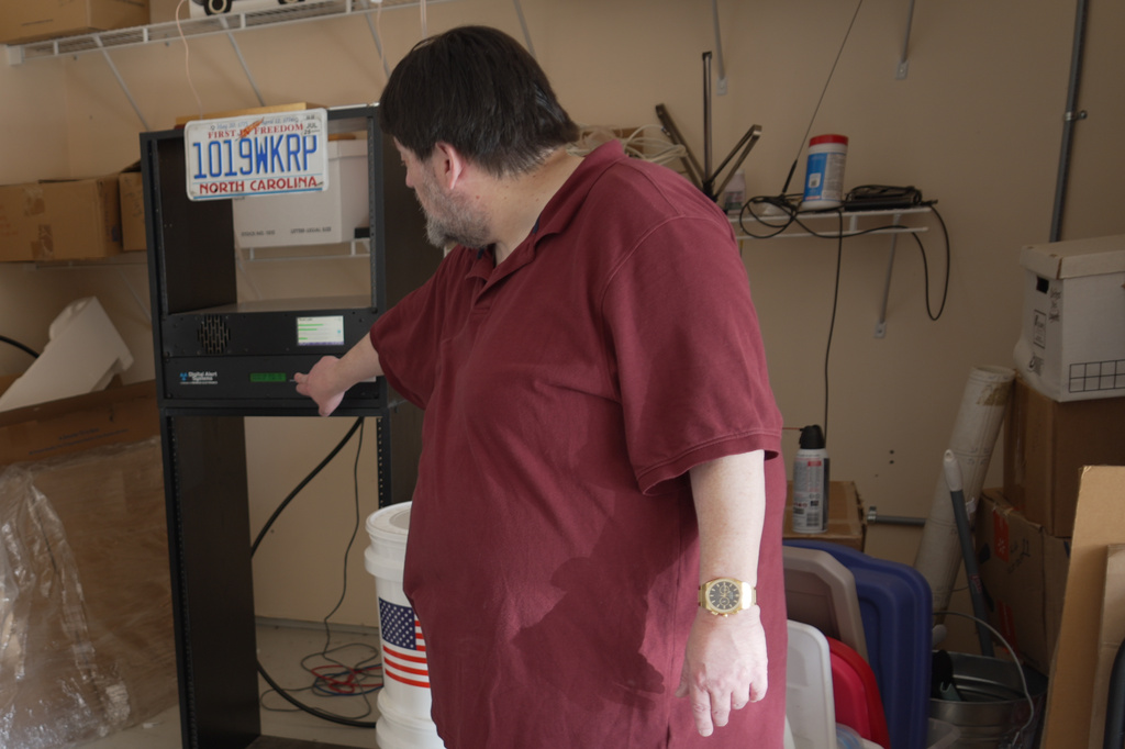 D.P. McIntire points to the transmitter for WKRP radio in a corner of his garage in Raleigh, N.C., on Thursday, April 2, 2026. (AP Photo/Allen G. Breed)