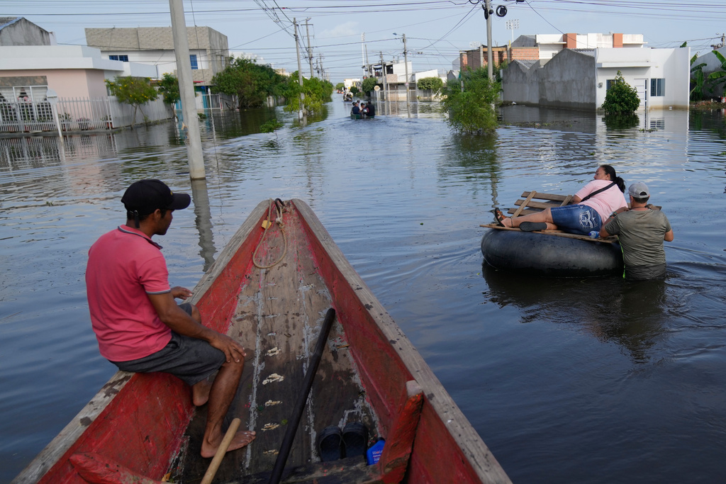 Residents wade through a flooded neighborhood in Monteria, Colombia, Tuesday, Feb. 10, 2026. (AP Photo/Fernando Vergara)