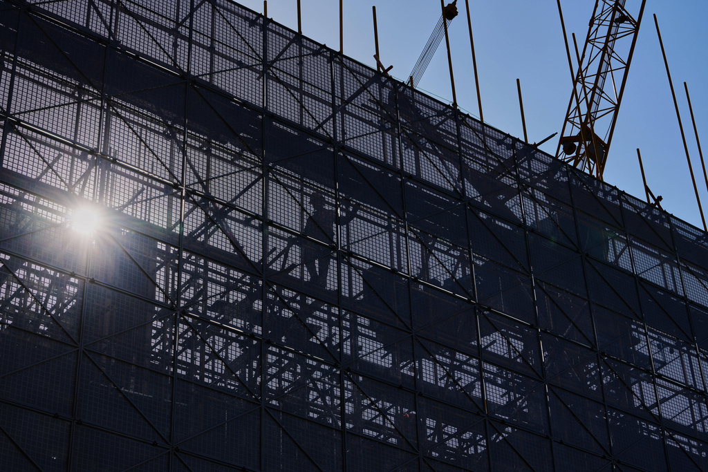 A worker installs scaffolding at a building under construction at the capital popular shopping district, in Beijing, Tuesday, Oct. 21, 2025. (AP Photo/Andy Wong)