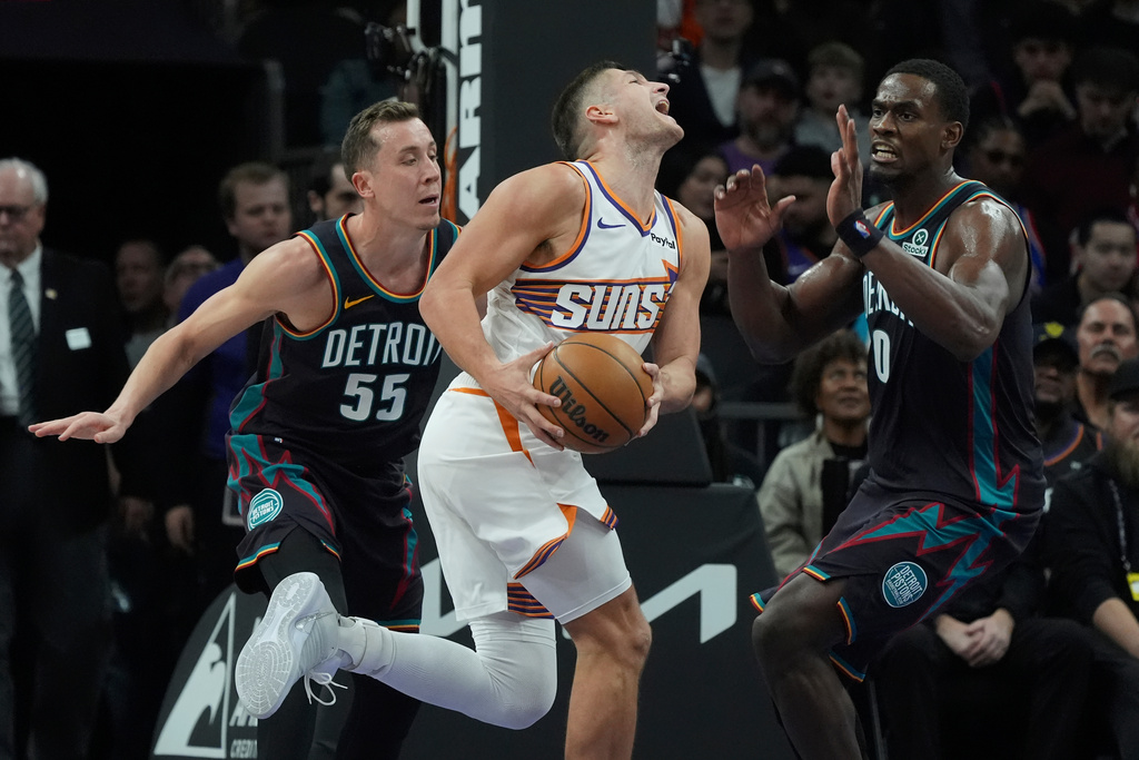Phoenix Suns guard Grayson Allen, center, is fouled by Detroit Pistons forward Duncan Robinson (55) as Pistons center Jalen Duren (0) arrives to defend during the first half of an NBA basketball game Thursday, Jan. 29, 2026, in Phoenix. (AP Photo/Ross D. Franklin)