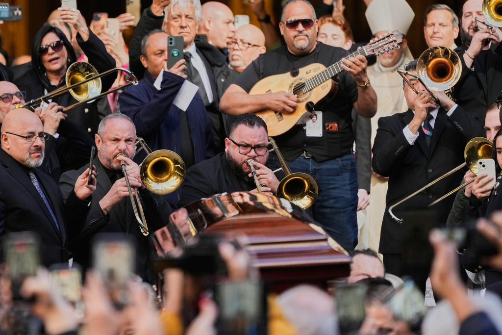 Musicians, primarily trombonists, play music as the body of Willie Colon leaves St. Patrick's Church during in New York, Monday, March 9, 2026. (AP Photo/Seth Wenig)