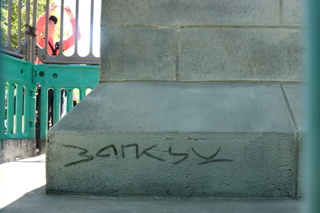 A signed 'Banksy is seen at a statue of a man holding a flag which covers his face, in Waterloo Place in London, Thursday, April 30, 2026. (AP Photo/Kin Cheung)